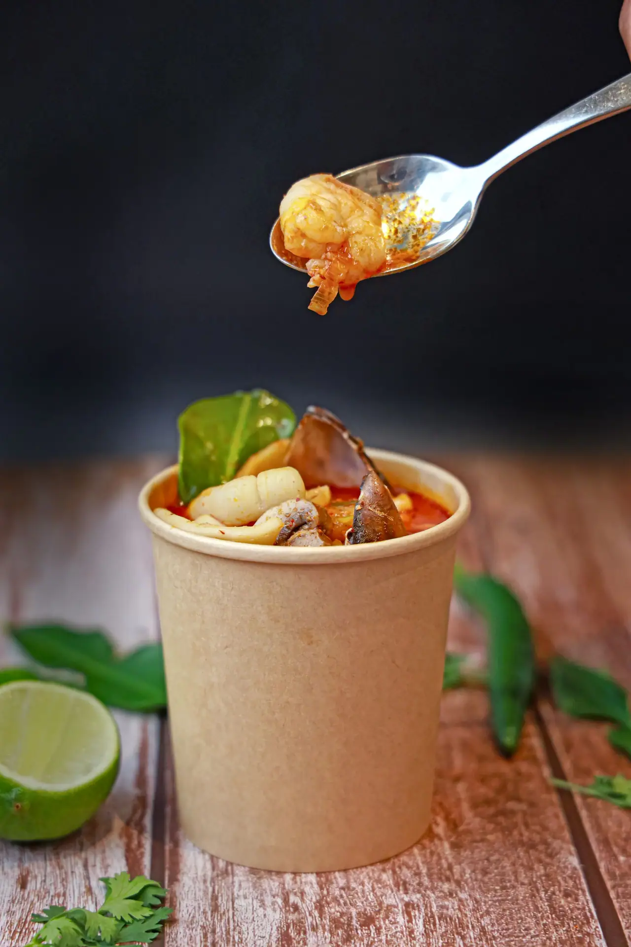 Soup in a kraft paper tub with lime and herbs