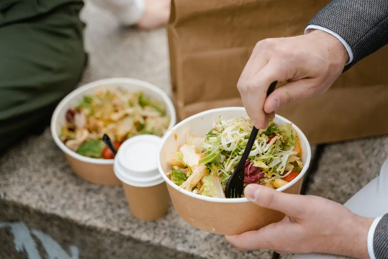 Salad eaten from a paper bowl with a coffee cup beside it